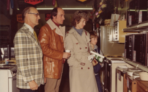 family being shown appliances in vintage photograph